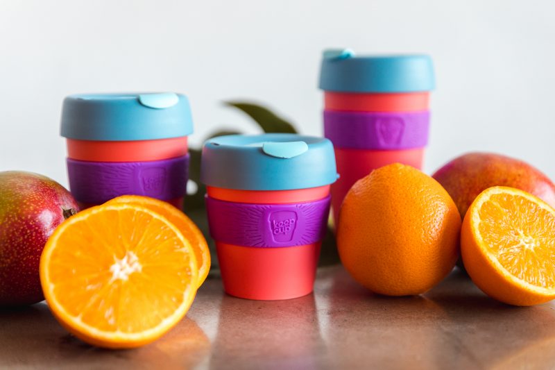 Pomarańcze i jabłka przy kubkach KeepCup